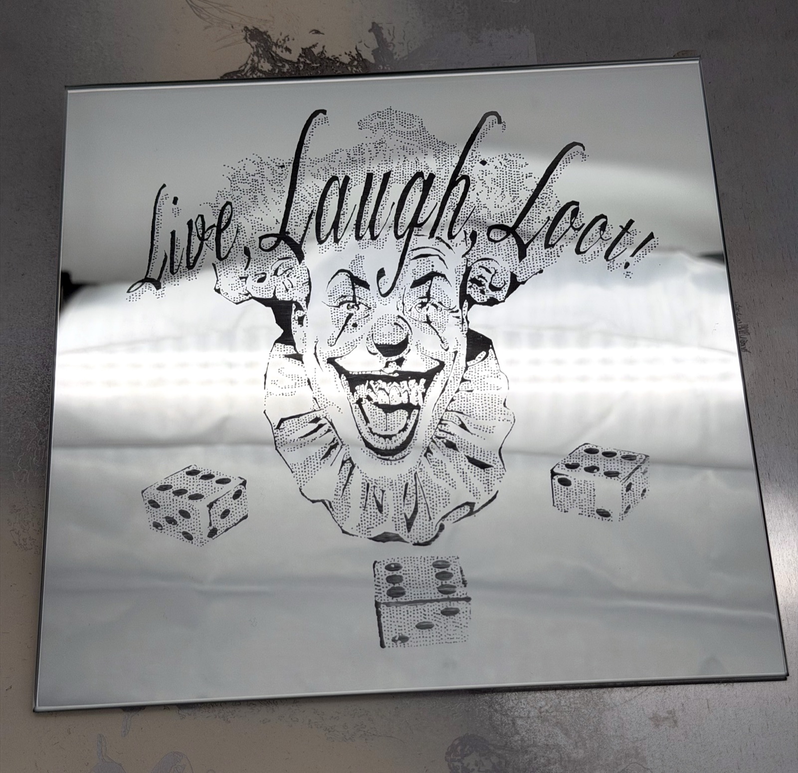 Rectangular mirror engraved with a stippled clown portrait, three dice and the script Live, Laugh, Loot!